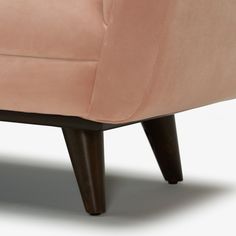 the back end of a pink chair with wooden legs and an upholstered seat