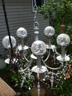 a metal chandelier with glass balls hanging from it's sides and flowers in the background