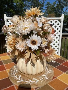 a vase filled with flowers sitting on top of a table next to a white fence