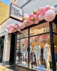 a storefront with balloons and mannequins in the window