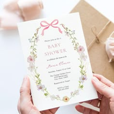 a person holding up a baby shower card next to a box with pink flowers on it