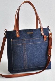 a denim bag with leather handles and straps on the front, sitting against a white background