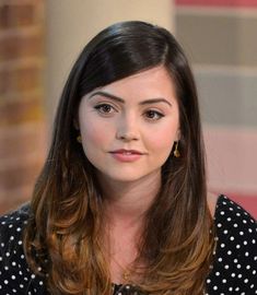 a close up of a person wearing a polka dot shirt and gold earrings