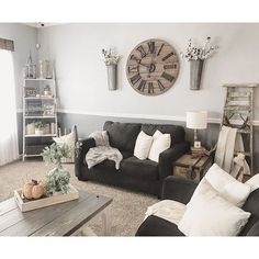 a living room filled with furniture and a large clock mounted to the wall above it