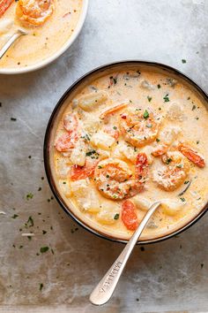 two bowls of soup with shrimp and dumplings in them on a white counter top