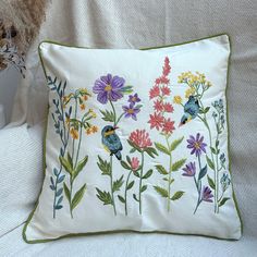 an embroidered pillow with flowers and birds on it