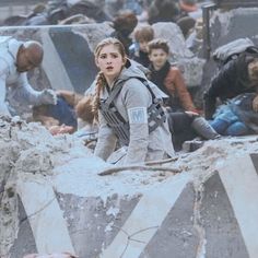 a woman standing on top of a pile of rubble next to other people in the background