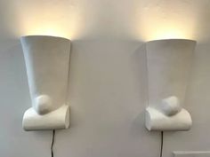 two white vases are on the wall next to each other, one is plugged in