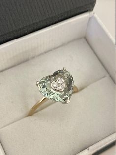 "This stunning ring is made from 14-karat two tone gold and set with beautiful heart shape of mint-green amethyst that set with three small sparkling diamonds at the center of the amethyst - which is said to have a calming effect on the soul and spirit. We believe this would be a thoughtful gift to give or treat to yourself. Material: 14k two tone gold Stone/Pendant: Green amethyst measures approximate 12.5 x 12.0 mm Diamonds: Approximate weigh 0.10-carats total Ring size: 9 US Weight: 3.3 grams Yellow Gold Green Amethyst Ring For Anniversary, Anniversary Green Amethyst Ring In Yellow Gold, Anniversary Green Amethyst Ring In Fine Jewelry Style, Fine Jewelry Green Amethyst Ring For Anniversary, Soul And Spirit, Green Amethyst Ring, Halo Earrings Studs, Amethyst Gem, Green Amethyst