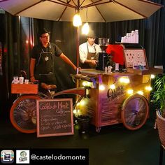 two men standing behind an ice cream cart with lights on the front and back wheels