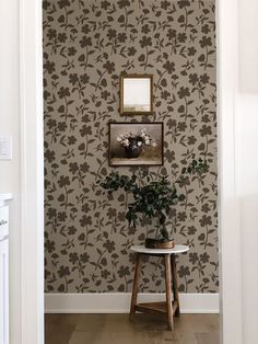 a vase with flowers sitting on top of a table in front of a wall paper