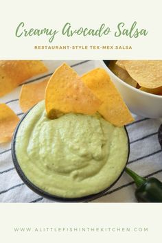 a bowl filled with guacamole and chips next to some tortilla chips