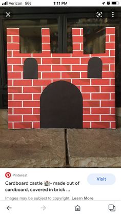 the cardboard castle is made out of cardboard, covered in brick and has black windows