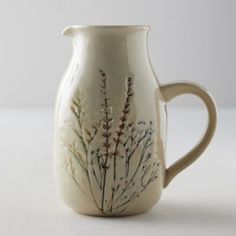 a white vase with plants painted on it