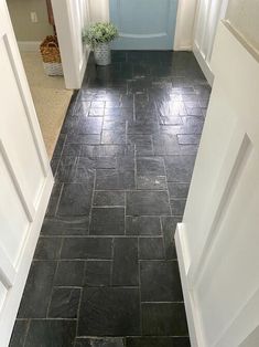 an empty hallway with blue door and black slate tile flooring in the entry way