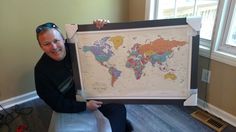 a man sitting on a couch holding up a framed map