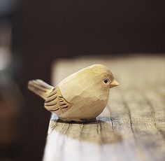 a small wooden bird sitting on top of a wooden table