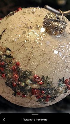 a close up of a christmas ball ornament on a metal hook with red and green decorations