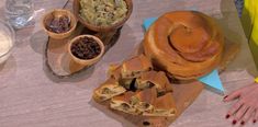 a table topped with lots of food on top of wooden trays next to bowls