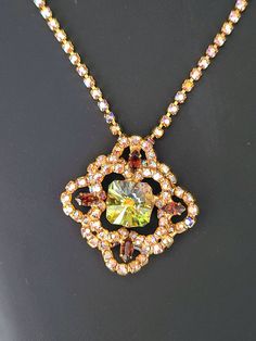 Vintage Vitrail Medium Rivoli Stone, Topaz and AB Rhinestone Necklace Glittering necklace consists of a sparkling AB rhinestone chain with a Maltese cross style pendant framed in AB rhinestones, dotted with 4 topaz navettes and centered with an eye catching vitrail medium octagon cut rivoli stone. All stones are prong set in shiny gold tone metal. Necklace chain measures 18 1/2 inches end to end and is adjustable shorter with the hook style clasp. Maltese cross pendant portion measures 1 3/4 inches by 1 3/4 inches and features a hidden bale. This unsigned beauty is in excellent vintage condition. Visit my shop at JanesVintageJewels.etsy.com Rhinestone Chain, Maltese Cross, Metal Necklace, Rhinestone Bracelet, Cool Necklaces, Rhinestone Necklace, Necklace Chain, Gold Tone Metal, Cross Pendant