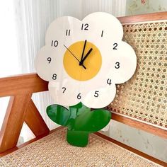 a clock that is sitting on top of a wooden chair with a flower in the middle