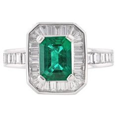 This ring is made in platinum and features an emerald cut, GIA certified emerald as the middle stone weighing 1.55 carats. The GIA certificate number is 2125281009. The ring also features 43 channel set, baguette cut diamonds weighing 1.23 carats. Platinum Baguette Cut Green Emerald Ring, Classic Green Emerald Ring With Baguette Diamonds, Gia Certified Octagon Emerald Ring In White Gold, Gia Certified White Gold Octagon Emerald Ring, Fine Jewelry Platinum Emerald Cut Emerald Ring, Classic Green Diamond Ring With Baguette Diamonds, Gia Certified Baguette Cut Emerald Ring, Green Emerald Cut Emerald Ring With Baguette Diamonds, Green Emerald Ring With Baguette Diamonds