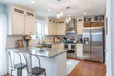 a kitchen with white cabinets, stainless steel appliances and an island in front of the stove