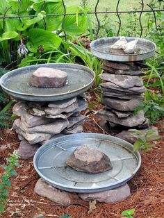 three plates stacked on top of each other with rocks in the middle and green plants behind them