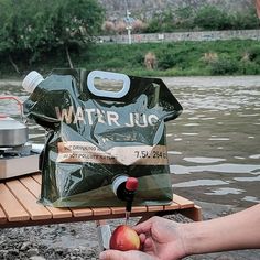 a person holding an apple near a bag of water jugs