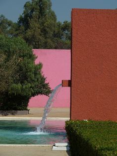 a fire hydrant spewing water out of it's side in front of a pink building