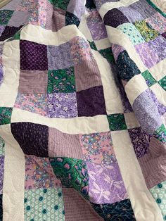 a purple and green patchwork quilt on a bed