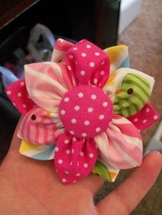 a hand holding a pink and green flower with polka dots