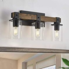 a bathroom vanity light with three lights and a wood frame over the mirror, hanging on a white wall