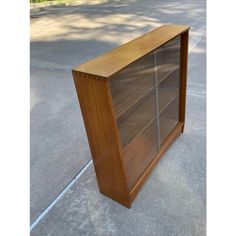 a wooden book case sitting on the sidewalk