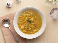 a white bowl filled with soup next to two spoons and a napkin on top of a table