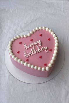 a heart shaped birthday cake with the words happy birthday written in frosting on it