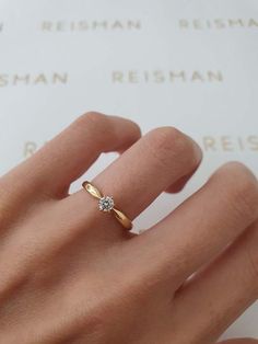 a woman's hand with a diamond ring on top of her finger, next to a white background