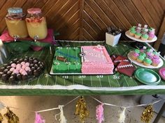 a table topped with cakes and cupcakes on top of a football field