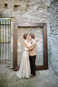 a man and woman standing next to each other in front of a photo frame with flowers