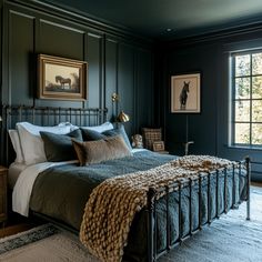 a bedroom with dark green walls and an iron bed frame in the middle, along with two framed pictures on the wall