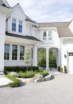 a large white house with lots of windows and bushes in front of the entrance to it