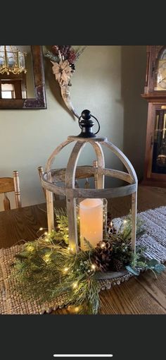 a candle is lit on top of a table with pine cones and greenery around it