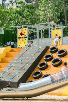 children playing on an inflatable slide at a playground with rubber tires and climbing ropes