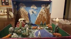 an open suitcase sitting on top of a table filled with fake trees and snow covered mountains