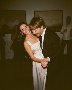 a man and woman are dancing together in a room with pictures on the wall behind them