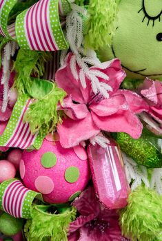 a green teddy bear sitting on top of a pile of pink and green ornaments