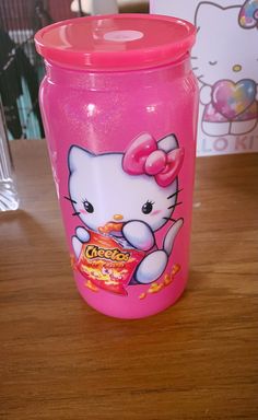 a pink hello kitty cup sitting on top of a wooden table