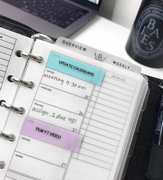 an open planner sitting on top of a desk next to a laptop