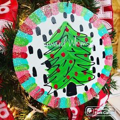 a christmas ornament hanging on a tree with red and green ribbon around it