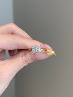 a woman's hand holding an engagement ring with a diamond in the middle and a gold band around it